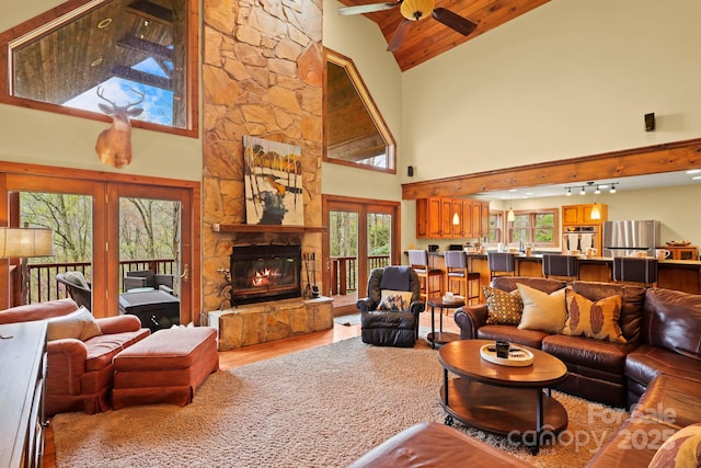 40 Ollis Ridge Ln, Elk Park, NC 28622 - living room featuring wood finished floors, a ceiling fan, high vaulted ceiling, a stone fireplace, and french doors