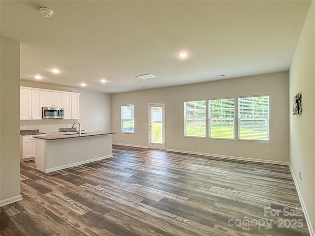 414 1st Ave SE, Hickory, NC 28602 - kitchen with stainless steel microwave, dark wood-type flooring, baseboards, white cabinetry, and a sink