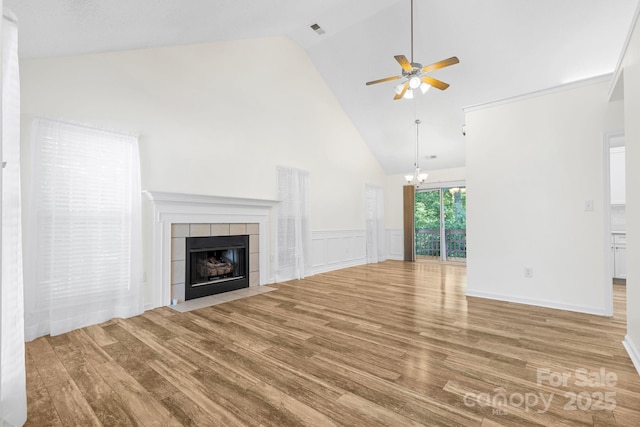 131 Canopy Ct, Mooresville, NC 28115 - unfurnished living room featuring wood finished floors, ceiling fan, high vaulted ceiling, a tiled fireplace, and a chandelier