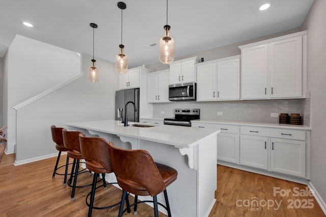 1315 Elizabeth Ave, Kannapolis, NC 28083 - kitchen with appliances with stainless steel finishes, decorative backsplash, a kitchen breakfast bar, light countertops, and recessed lighting