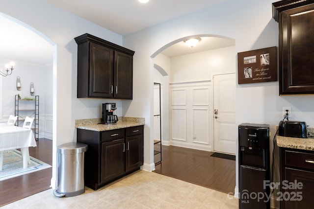 2405 Emma Grace Ln, Rock Hill, SC 29732 - kitchen with arched walkways, dark brown cabinetry, light stone counters, and light wood finished floors