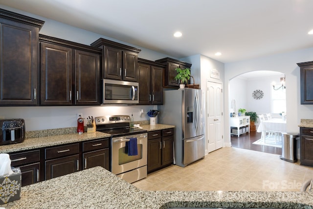 2405 Emma Grace Ln, Rock Hill, SC 29732 - kitchen with appliances with stainless steel finishes, arched walkways, dark brown cabinetry, light stone countertops, and recessed lighting