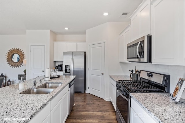 3908 Coleman Dr, Charlotte, NC 28215 - kitchen featuring appliances with stainless steel finishes, a sink, white cabinets, dark wood-style flooring, and light stone counters