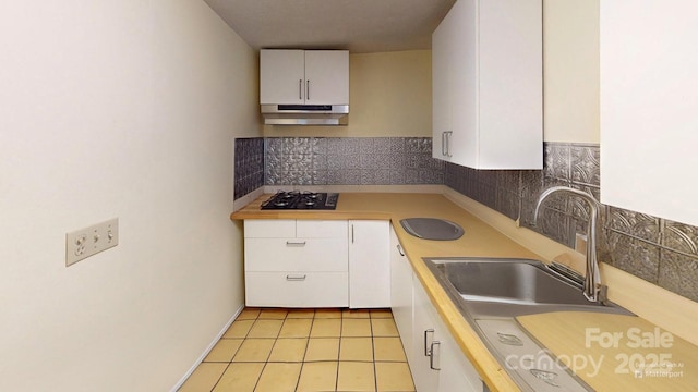4584 NC Highway 194 S, Banner Elk, NC 28604 - kitchen with under cabinet range hood, black gas cooktop, light countertops, white cabinets, and tasteful backsplash