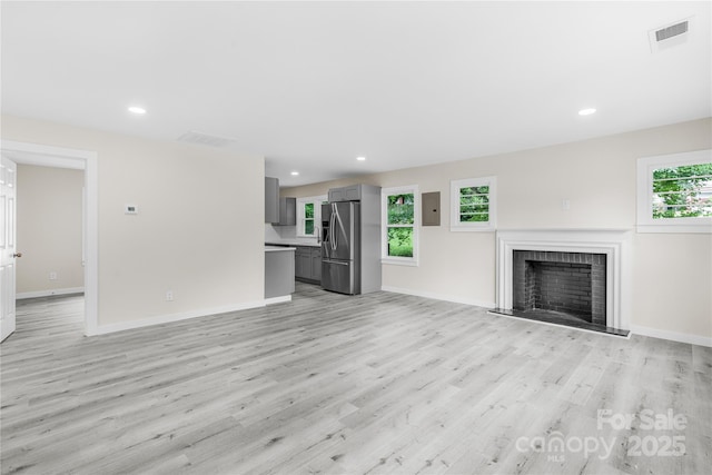 1017 W Fisher St, Salisbury, NC 28144 - unfurnished living room featuring light wood-type flooring, a brick fireplace, electric panel, and recessed lighting