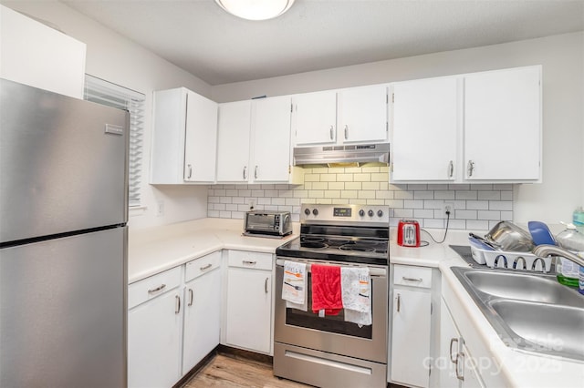 1602 Eagles Pl Unit J103, Rock Hill, SC 29732 - kitchen featuring appliances with stainless steel finishes, under cabinet range hood, light countertops, light wood-style floors, and decorative backsplash