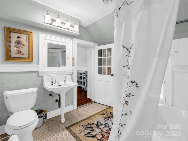 287 Pacolet Ridge Ln, Tryon, NC 28782 - bathroom featuring lofted ceiling, a wainscoted wall, shower / tub combo with curtain, tile walls, and tile patterned floors