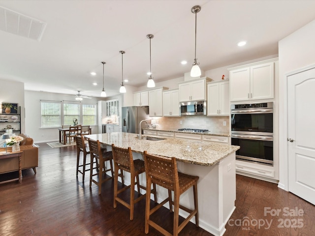 8035 Pastime Ln, Clover, SC 29710 - kitchen with appliances with stainless steel finishes, recessed lighting, a breakfast bar area, a kitchen island with sink, and white cabinets