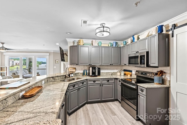 860 Jetton St Unit 59, Davidson, NC 28036 - kitchen featuring gray cabinetry, stainless steel appliances, light wood-style flooring, decorative backsplash, and crown molding