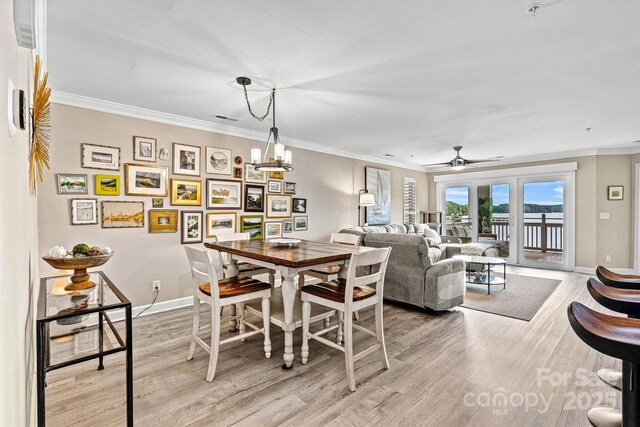 860 Jetton St Unit 59, Davidson, NC 28036 - dining space featuring light wood-style flooring, crown molding, a water view, ceiling fan, and a chandelier