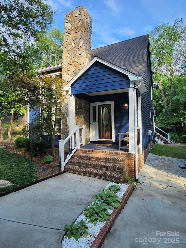 27092 Village Dr, Tega Cay, SC 29708 - view of exterior entry with a chimney and a shingled roof