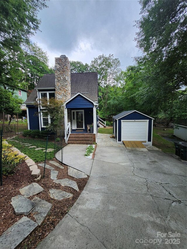 27092 Village Dr, Tega Cay, SC 29708 - view of front of property featuring a detached garage, concrete driveway, an outdoor structure, a shingled roof, and a chimney