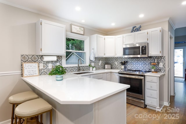 27092 Village Dr, Tega Cay, SC 29708 - kitchen featuring stainless steel appliances, a peninsula, light wood-type flooring, backsplash, and ornamental molding