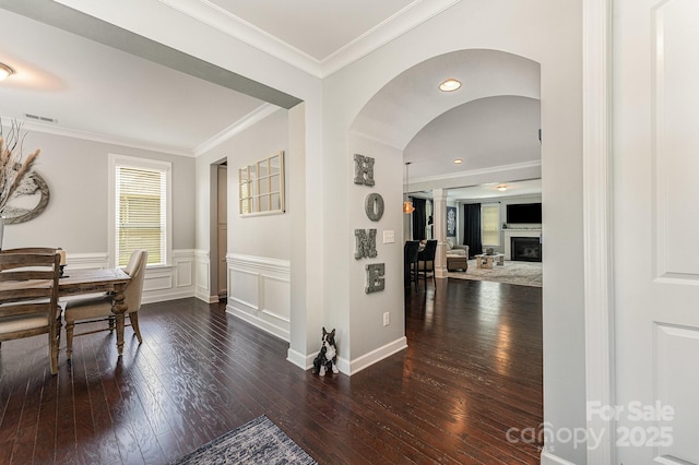 2606 Cheverny Pl, Concord, NC 28027 - hallway featuring arched walkways, wood-type flooring, ornamental molding, and a wainscoted wall