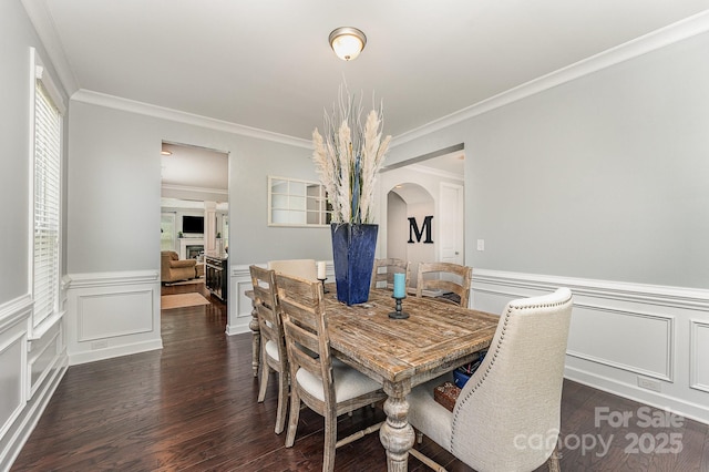2606 Cheverny Pl, Concord, NC 28027 - dining area featuring arched walkways, crown molding, wood finished floors, wainscoting, and a decorative wall