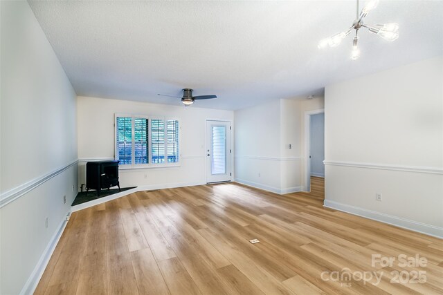 234 Wash Creek Dr Unit B, Hendersonville, NC 28739 - unfurnished living room featuring a wood stove, light wood-type flooring, a chandelier, and a ceiling fan