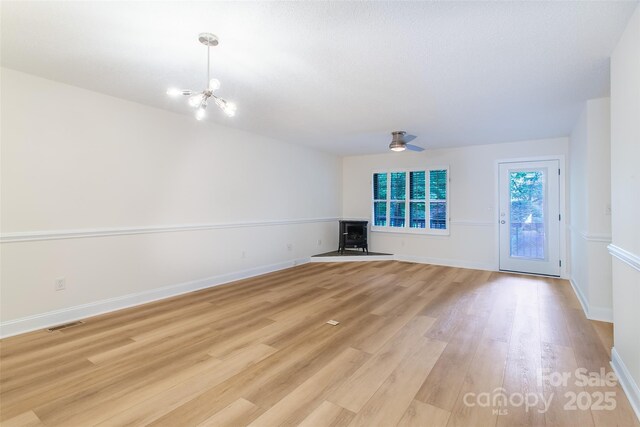 234 Wash Creek Dr Unit B, Hendersonville, NC 28739 - unfurnished living room featuring a wood stove, a chandelier, light wood-style floors, and ceiling fan