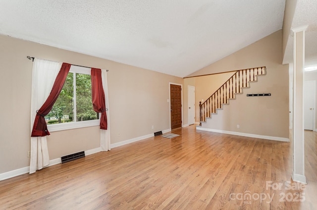 110 Hidden Valley St, Cherryville, NC 28021 - unfurnished living room featuring light wood-style floors, stairway, lofted ceiling, and a textured ceiling