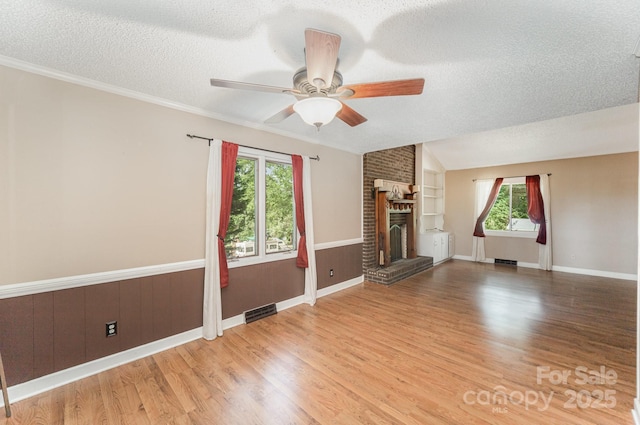 110 Hidden Valley St, Cherryville, NC 28021 - unfurnished living room with a textured ceiling, a ceiling fan, a fireplace, wood finished floors, and ornamental molding