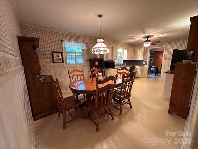 211 S Slack St, Albemarle, NC 28001 - dining space featuring wallpapered walls, a ceiling fan, crown molding, wainscoting, and light flooring