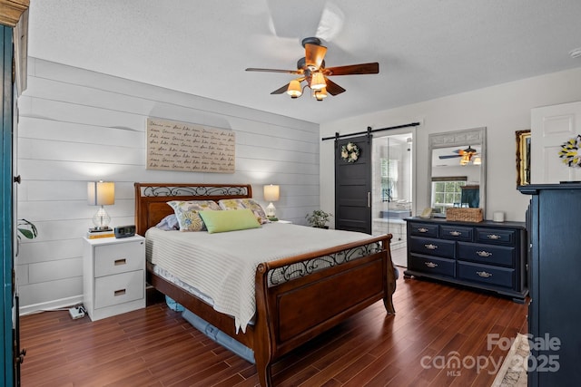 8700 Fox Tail Ln, Huntersville, NC 28078 - bedroom with a barn door, dark wood-style flooring, wood walls, and a ceiling fan