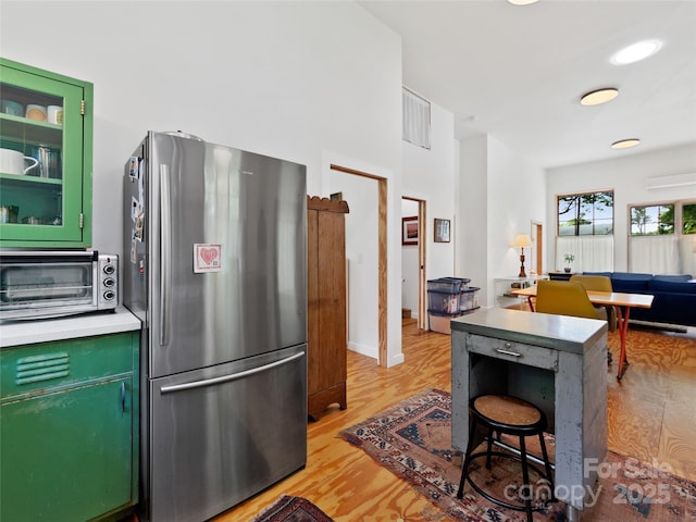 59 Alexander Rd, Weaverville, NC 28787 - kitchen featuring freestanding refrigerator, green cabinetry, light wood-type flooring, glass insert cabinets, and light countertops
