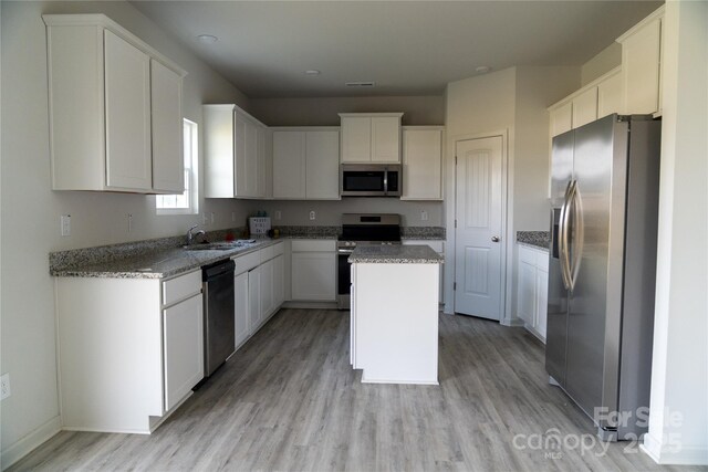 69 Ravibha Ct, Clayton, NC 27520 - kitchen with stainless steel appliances, light wood-type flooring, a sink, a kitchen island, and white cabinets