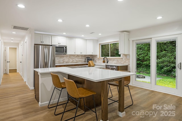 487 Duncan Creek Rd, Fletcher, NC 28732 - kitchen featuring stainless steel appliances, decorative backsplash, a center island, white cabinets, and a breakfast bar