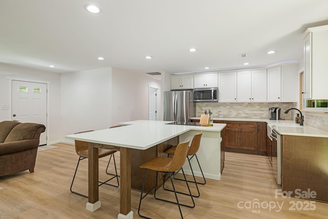 487 Duncan Creek Rd, Fletcher, NC 28732 - kitchen with appliances with stainless steel finishes, light wood-type flooring, a kitchen island, a breakfast bar, and recessed lighting