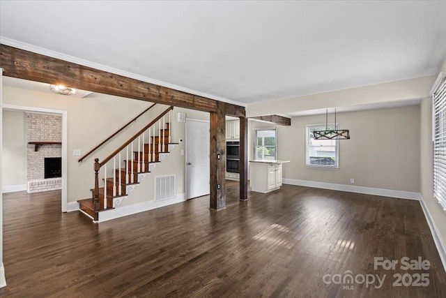 5811 Gettysburg Dr, Concord, NC 28027 - unfurnished living room featuring a brick fireplace, stairs, dark wood-style flooring, and a chandelier