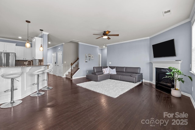 1569 Shannon Falls Dr, Fort Mill, SC 29715 - living area featuring a ceiling fan, crown molding, a glass covered fireplace, dark wood-style floors, and stairway