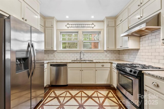 805 S Main St, Mount Holly, NC 28120 - kitchen featuring stainless steel appliances, inlaid floor details, under cabinet range hood, backsplash, and light stone countertops
