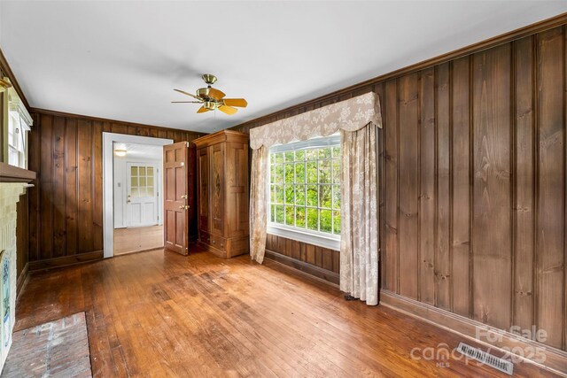 805 S Main St, Mount Holly, NC 28120 - unfurnished living room featuring wood walls, hardwood / wood-style floors, and ceiling fan