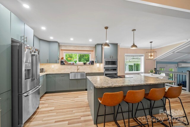 419 E Blue Ridge Rd, East Flat Rock, NC 28726 - kitchen featuring stainless steel appliances, light wood finished floors, a center island, backsplash, and plenty of natural light