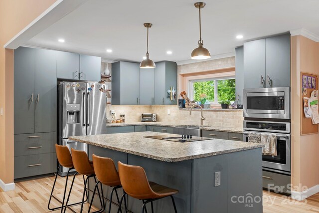 419 E Blue Ridge Rd, East Flat Rock, NC 28726 - kitchen with appliances with stainless steel finishes, light wood-type flooring, a kitchen bar, backsplash, and a center island