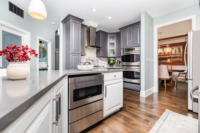 10203 Loch Lomond Dr, Charlotte, NC 28278 - kitchen featuring appliances with stainless steel finishes, wall chimney range hood, backsplash, dark wood-type flooring, and glass insert cabinets