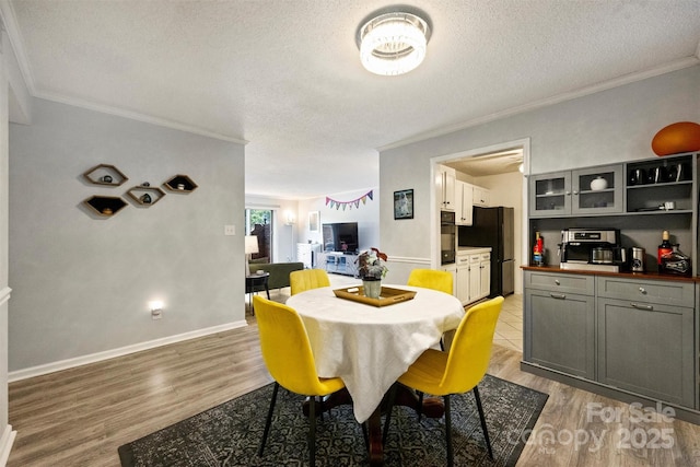 4736 Hedgemore Dr Unit K, Charlotte, NC 28209 - dining room featuring crown molding, light wood-style floors, and a textured ceiling