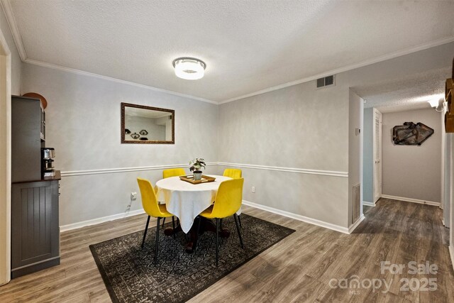 4736 Hedgemore Dr Unit K, Charlotte, NC 28209 - dining space featuring wood finished floors, a textured ceiling, and ornamental molding