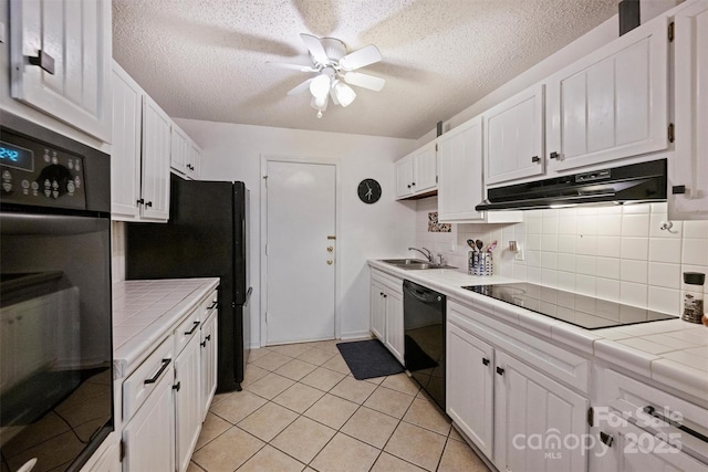 4736 Hedgemore Dr Unit K, Charlotte, NC 28209 - kitchen featuring tile counters, under cabinet range hood, black appliances, white cabinets, and a ceiling fan