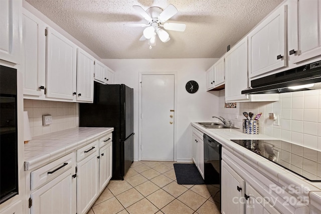 4736 Hedgemore Dr Unit K, Charlotte, NC 28209 - kitchen with tile countertops, under cabinet range hood, black appliances, white cabinets, and a textured ceiling