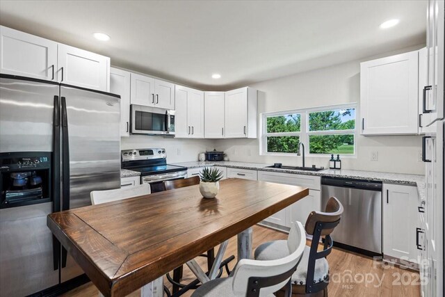 5740 Crouse Rd, Crouse, NC 28033 - kitchen with stainless steel appliances, white cabinetry, light stone countertops, recessed lighting, and light wood-style flooring