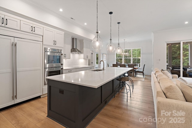 8283 Long Island Rd, Catawba, NC 28609 - kitchen with wall chimney exhaust hood, stainless steel double oven, open floor plan, ornamental molding, and white cabinetry