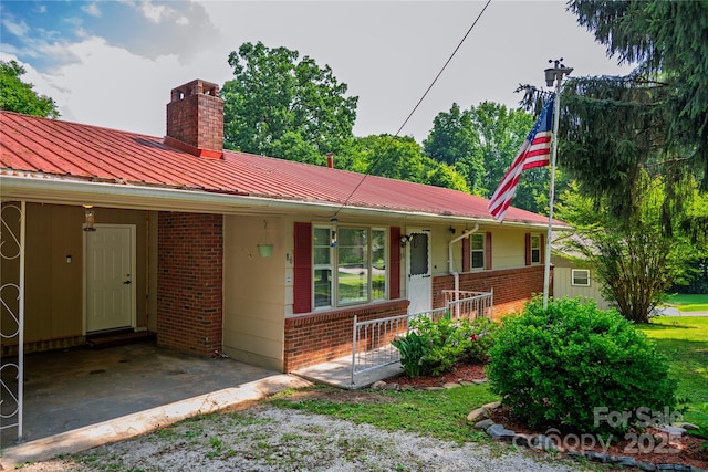 86 Pine Grove Dr, Andrews, NC 28901 - ranch-style home featuring brick siding, a chimney, a metal roof, covered porch, and an attached carport