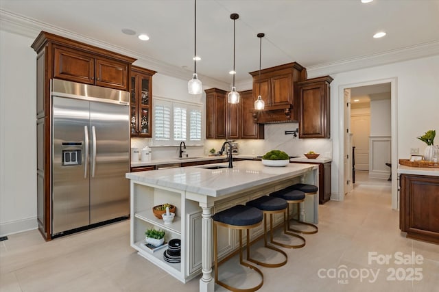 1500 Lookout Cir, Waxhaw, NC 28173 - kitchen featuring built in refrigerator, open shelves, a kitchen island with sink, light stone countertops, and decorative light fixtures