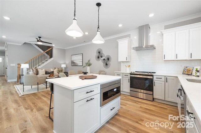 2003 Ashley Rd Unit B, Charlotte, NC 28208 - kitchen featuring stainless steel appliances, wall chimney range hood, ornamental molding, decorative backsplash, and a breakfast bar area