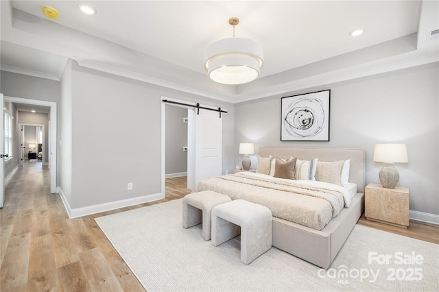 2003 Ashley Rd Unit B, Charlotte, NC 28208 - bedroom featuring a barn door, recessed lighting, light wood-style flooring, a raised ceiling, and ornamental molding