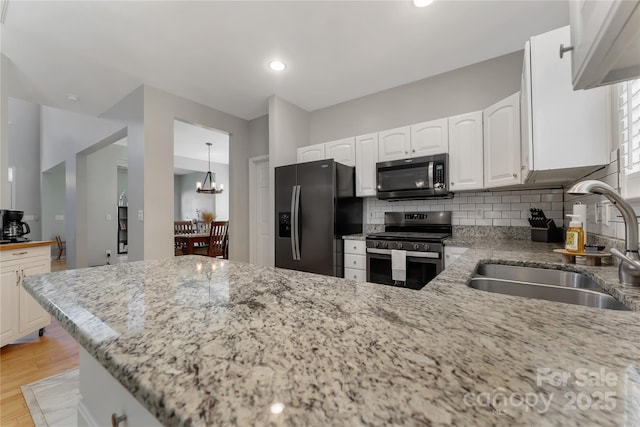 4000 Garfield Ct, Waxhaw, NC 28173 - kitchen with appliances with stainless steel finishes, light stone countertops, white cabinetry, decorative backsplash, and light wood finished floors