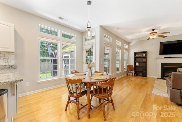 4000 Garfield Ct, Waxhaw, NC 28173 - dining area with light wood finished floors, a glass covered fireplace, and a ceiling fan