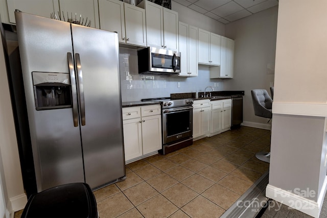 720 Governor Morrison St Unit 221, Charlotte, NC 28211 - kitchen featuring appliances with stainless steel finishes, dark countertops, white cabinets, a drop ceiling, and light tile patterned flooring