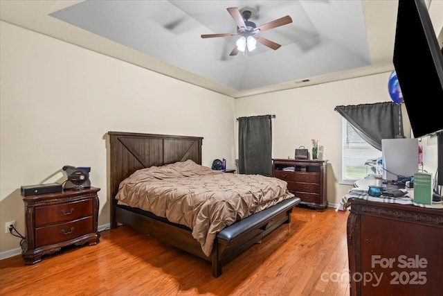 5111 Elementary View Dr, Charlotte, NC 28269 - bedroom featuring a raised ceiling, light wood-type flooring, and a ceiling fan